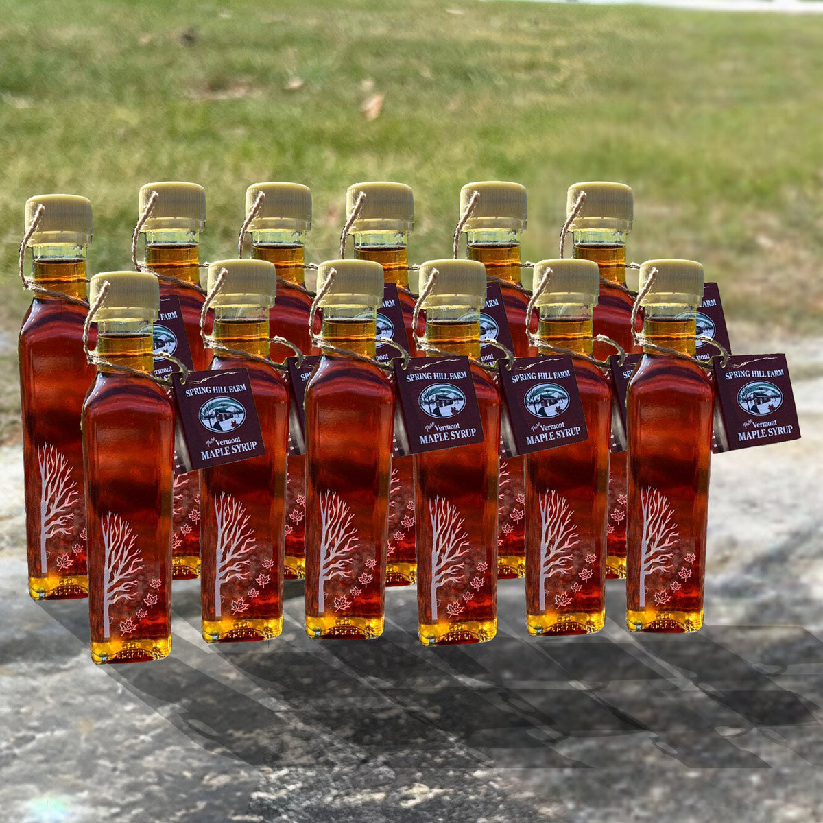 12 pack of engraved leaf maple syrup bottles sitting on a Vermont stone wall